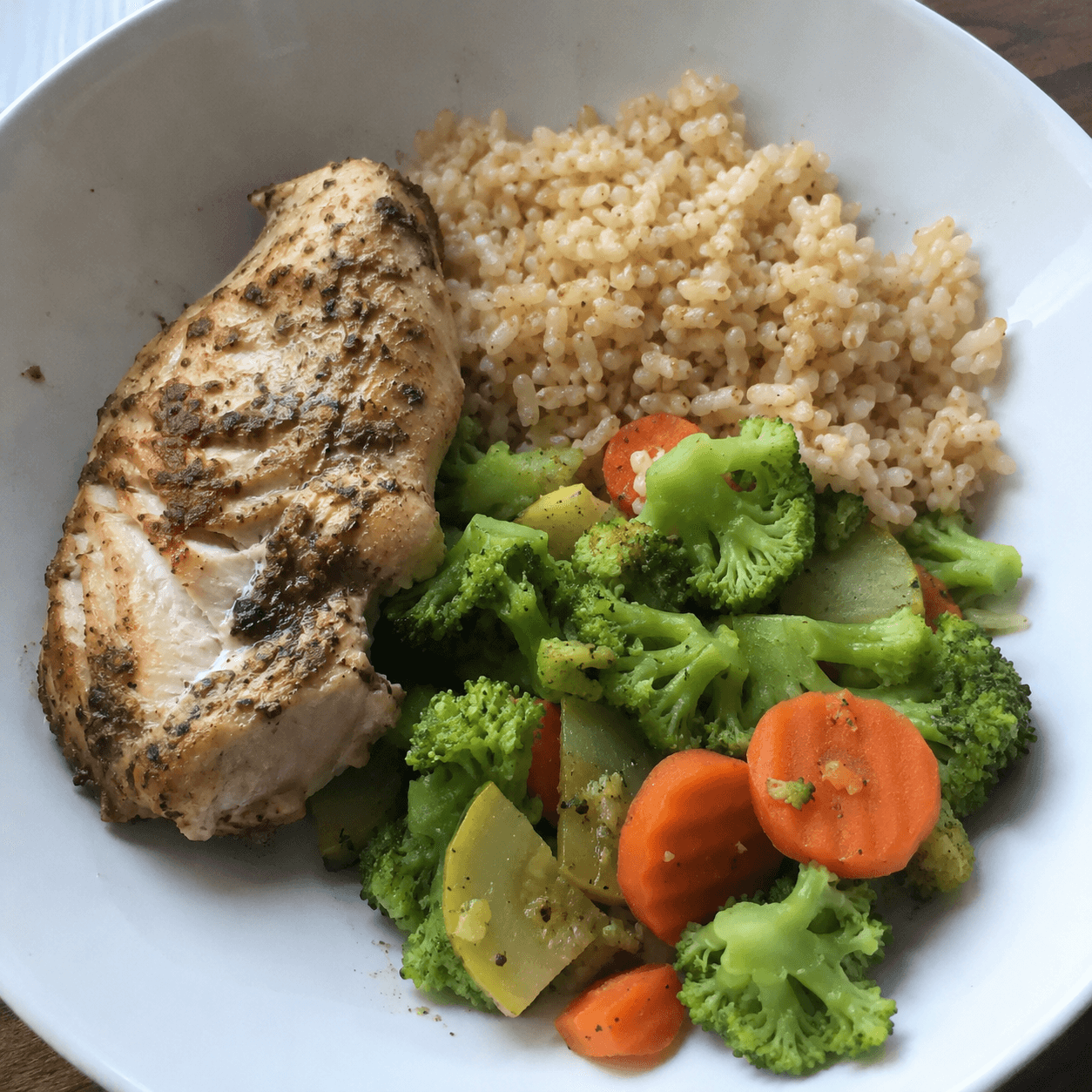 Chicken, broccoli, carrots, and cooked rice on a plate